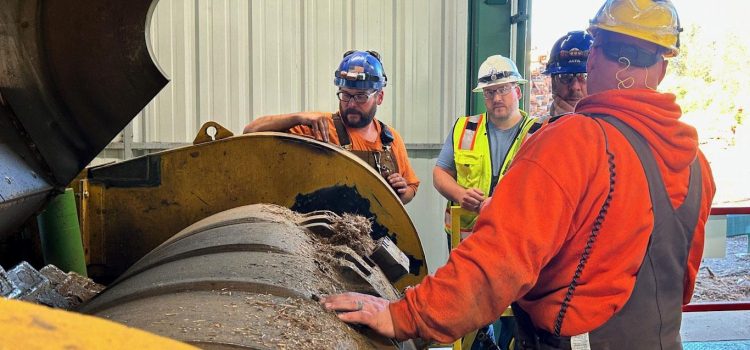 The Crada Project-Cooperative Research & Development Agreement A photograph of a Rawlings Industrial Wood Hog inside of a Washington State saw mill. There are four men with hard hats on standing and viewing the inside of the machines components.